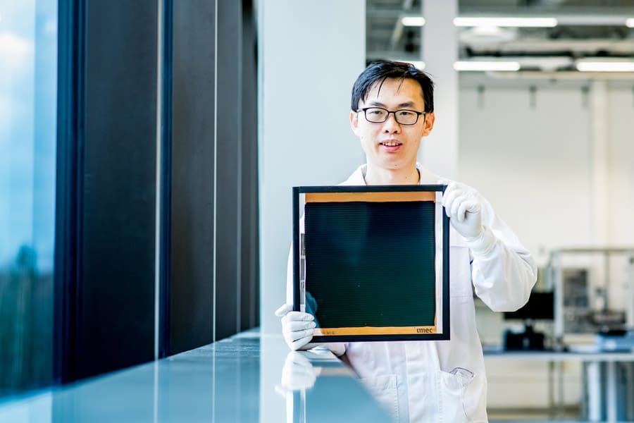 Alt text: A researcher holds a large 30x30 cm² perovskite module, demonstrating the advanced capabilities and research of the company's thin film deposition systems. The researcher, dressed in a lab coat and gloves, showcases the module in a laboratory setting, showcasing Angstrom Engineering's commitment to innovation in perovskite solar cell technology.